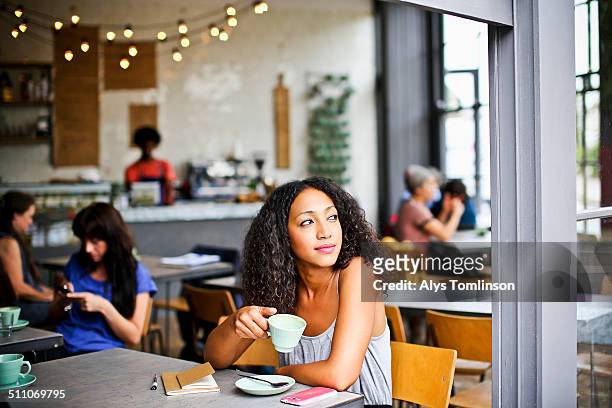 woman looking out of a cafe window - modern cafe stock pictures, royalty-free photos & images