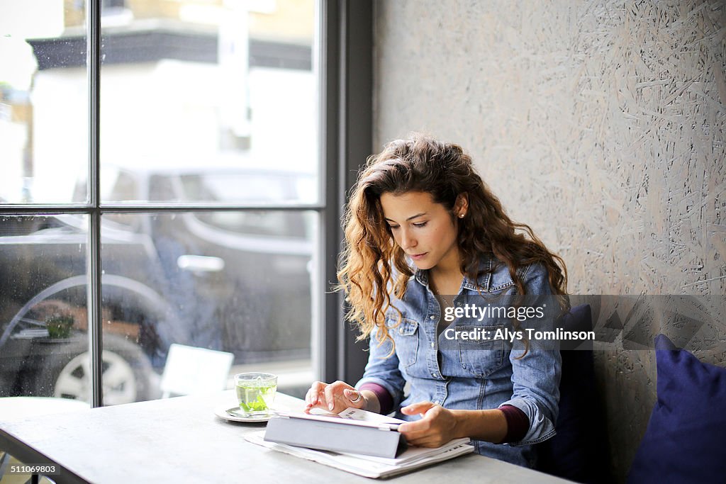 Woman Sitting in a Cafe Using a Tablet Computer