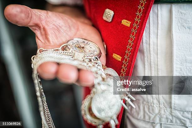 landwirt in der traditionellen schweizer kostüm schecks zeit auf taschenuhr - traditionelle kleidung stock-fotos und bilder