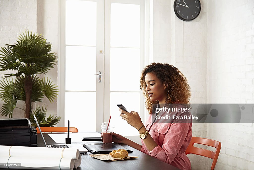 Young women in creative office using a mobile.