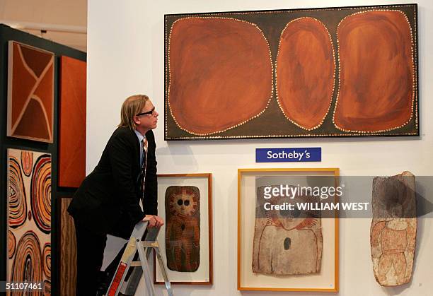 Director of Aboriginal Art at Sotheby's, Tim Klingender inspects a painting by Rover Thomas which is hoped to become the first painting by an...