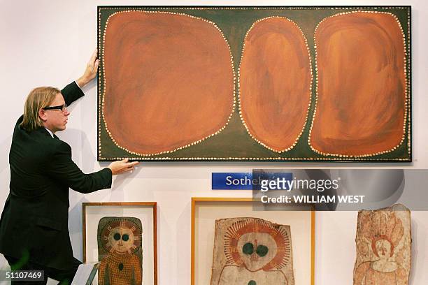Director of Aboriginal Art at Sotheby's, Tim Klingender adjusts a painting by Rover Thomas which is hoped to become the first painting by an...