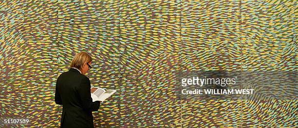 Director of Aboriginal Art at Sotheby's, Tim Klingender inspects a painting by aboriginal artist Gloria Tamerre Petyarre which is expected to sold...