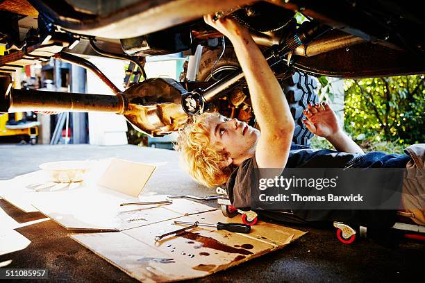 teenager lying on driveway replacing oil pan - cardboard car stock pictures, royalty-free photos & images