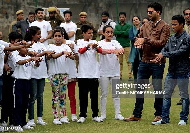 Indian cricketers Yuvraj Singh and Pawan Negi interact with children during an event to launch an initiative advocating for disadvantaged children...