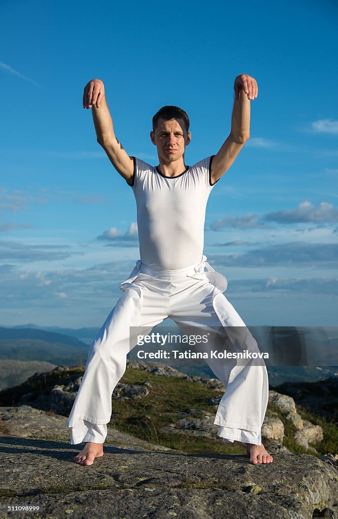 Young man exercising on top of a mountain