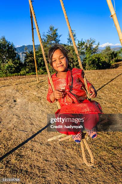 little girl swinging in village near bhaktapur, himalayas on background - nepal family stock pictures, royalty-free photos & images