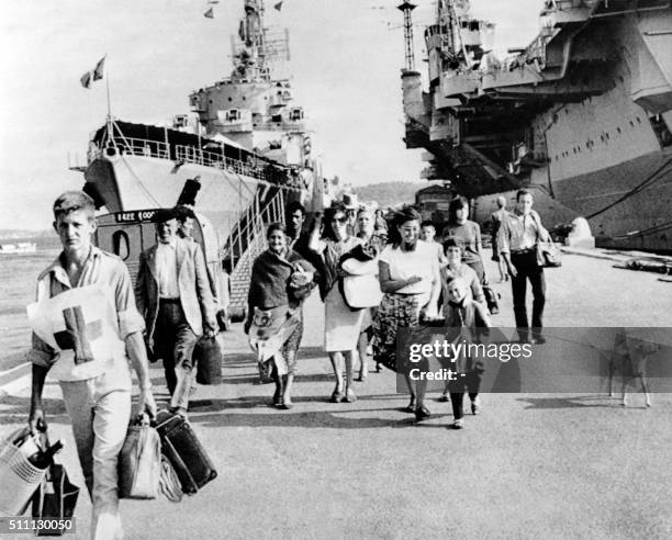 Des réfugiés en provenance de Mers-El-Kebir, accompagnés d'un secouriste, débarquent du porte-avions "La Fayette" à Toulon le 19 juillet 1962. Le La...