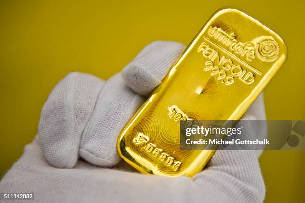 Muenchen, Germany A hand with glove holds a gold bar in the safe of Pro Aurum Gold trading house on February 16, 2016 in Muenchen, Germany.