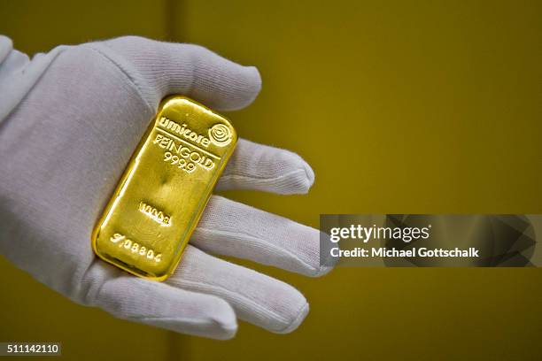 Muenchen, Germany A hand with glove holds a gold bar in the safe of Pro Aurum Gold trading house on February 16, 2016 in Muenchen, Germany.