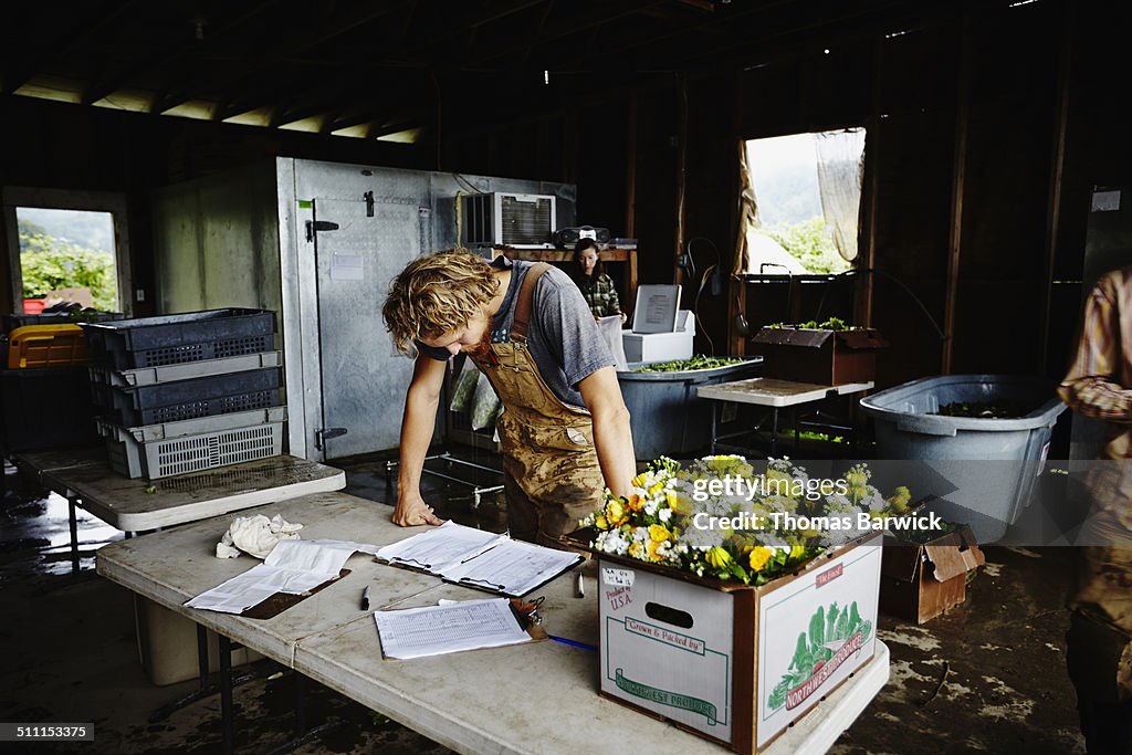 Farmer leaning on table checking delivery log