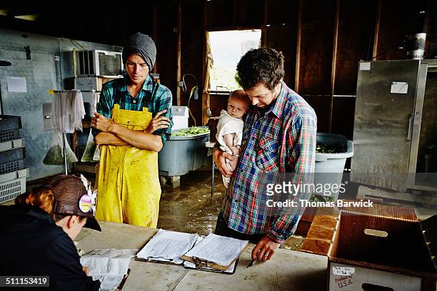 Farm owner holding infant looking over log