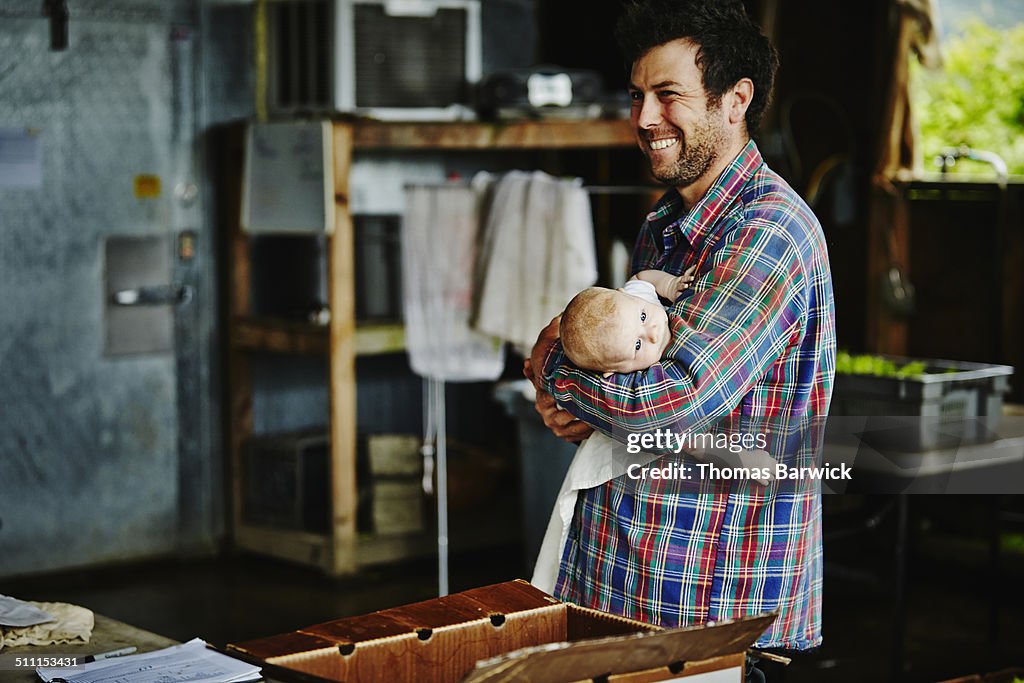 Farm owner holding infant daughter in work shed