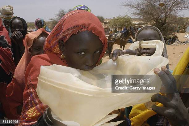 In this June 2004 handout Ten-year-old Nadifa Isadurgi drinks clean water in the Touloum refugee camp, near Iriba, Chad. Efforts are currently...
