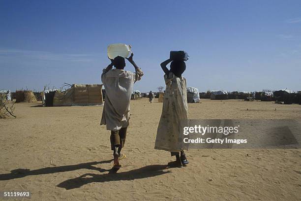 In this June 2004 handout two Sudanese refugees carry water to the Iridimi refugee camp in Chad. Efforts are currently underway July 27, 2004 to get...