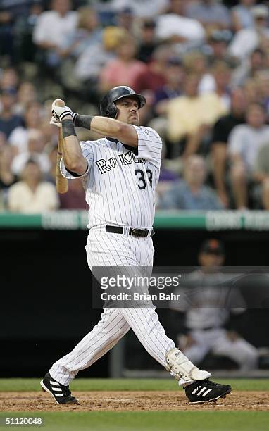 Right fielder Larry Walker of the Colorado Rockies watches the flight of the ball as he follows through on a swing during the game against the San...