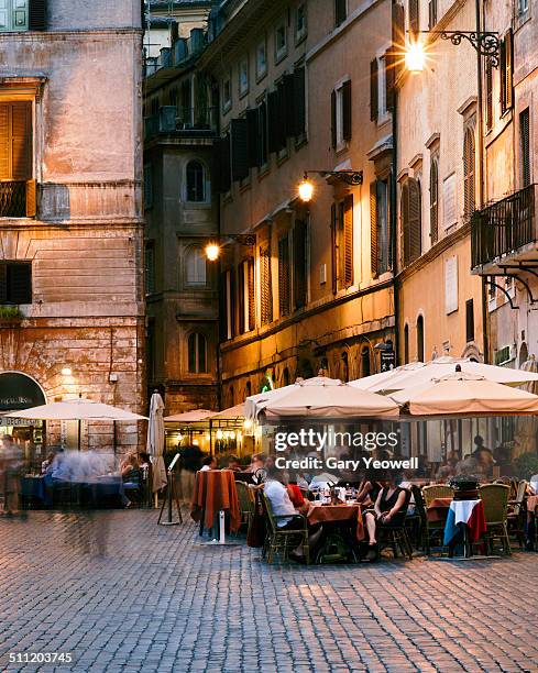 people sitting outside restaurants in a piazza - städtischer platz stock-fotos und bilder