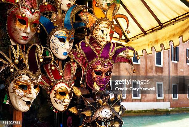 carnival masks on display by canal in venice - carnival venice stockfoto's en -beelden