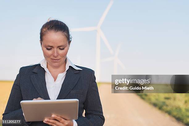 businesswoman using tablet pc near wind farm. - longeville sur mer stock pictures, royalty-free photos & images