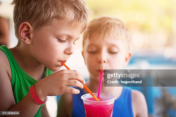 little boys drinking soda with crushed ice on summer day - frisdrank stockfoto's en -beelden