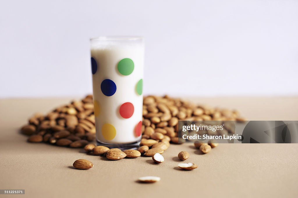 Almond milk in glass with raw almonds