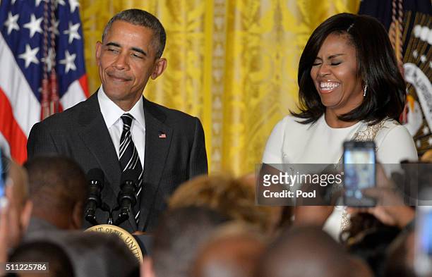 President Barack Obama speaks, as First Lady Michelle Obama listens, at a reception for Black History Month, in the East Room of the White House,...