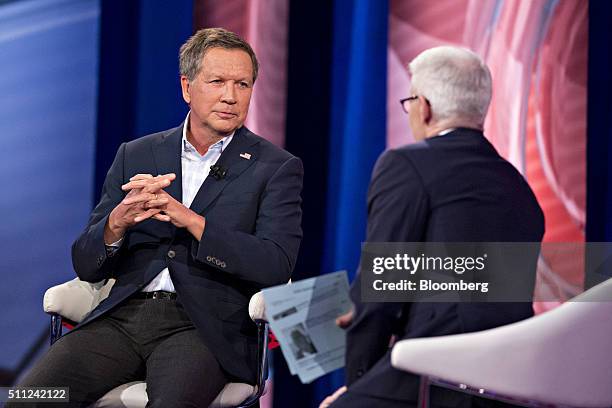 John Kasich, governor of Ohio and 2016 Republican presidential candidate, left, listens during a town hall event hosted by CNN anchor Anderson Cooper...