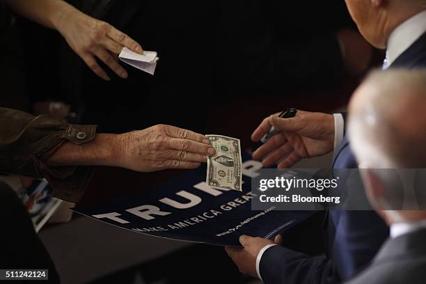 An attendee handles a U.S. Two dollar banknote to Donald Trump, president and chief executive of Trump Organization Inc. And 2016 Republican...