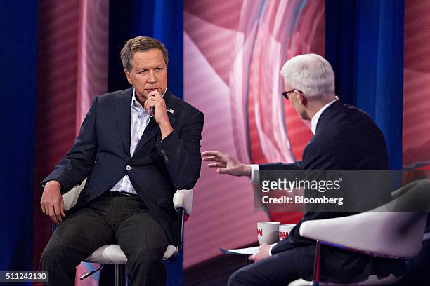 John Kasich, governor of Ohio and 2016 Republican presidential candidate, left, listens during a town hall event hosted by CNN and anchor Anderson...