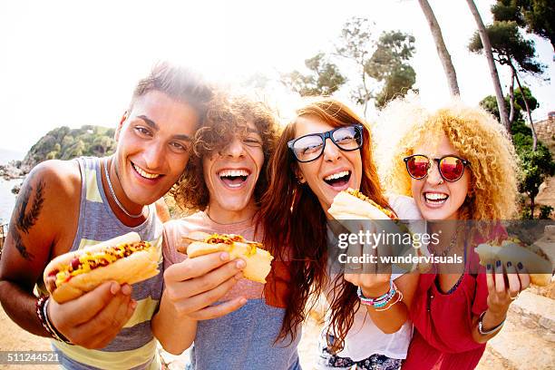 friends eating hotdogs - hotdog stockfoto's en -beelden