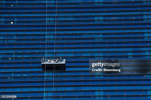 Laborers work at an elevated platform outside a building in the central business district in Singapore, on Thursday, Feb. 18, 2016. Singapore's...