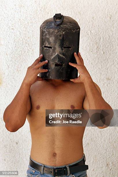 Iraqi security guard, Ayad Mutashar, shows off a mask that was one of the tools of torture that Saddam Hussein's slain son, Odai, is believed to have...