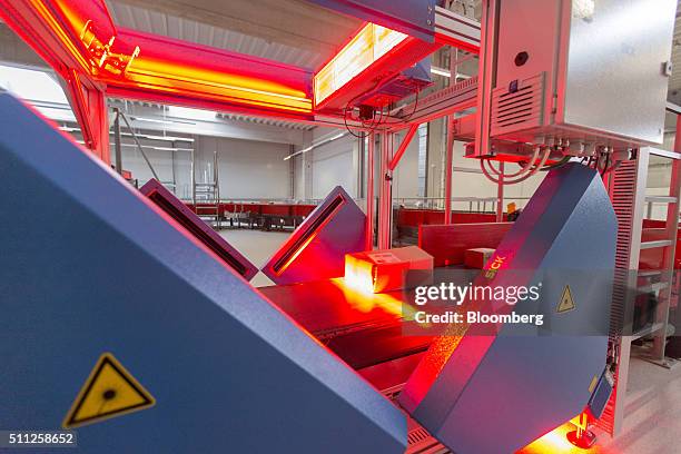 Parcel is illuminated by red sensor light beams as it passes through a scanning machine, manufactured by Sick AG, at a mechanized postal delivery...