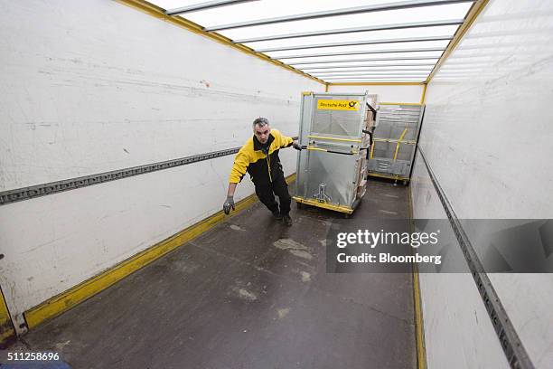 An employee pulls a mail cart from a delivery truck at a DHL parcel center, operated by Deutsche Post AG, in Saulheim, Germany, on Thursday, Feb. 18,...