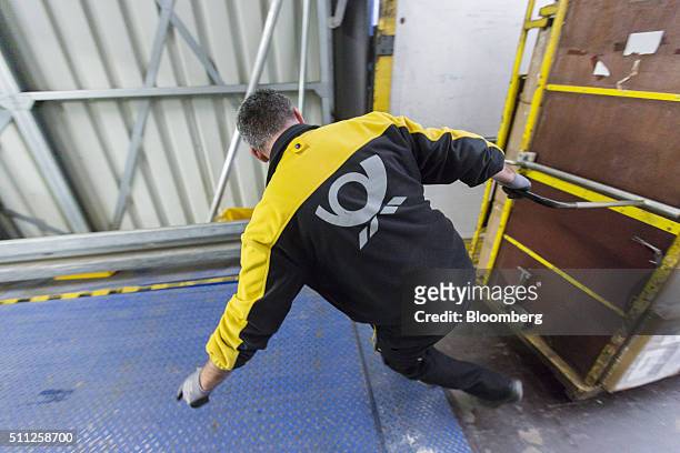 An employee pulls a mail cart from a delivery truck at a DHL parcel center, operated by Deutsche Post AG, in Saulheim, Germany, on Thursday, Feb. 18,...