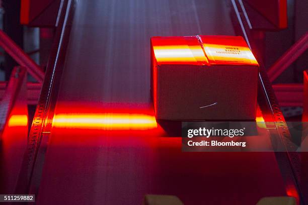 Parcel is illuminated by a red sensor light beam as it passes through a scanning machine at a mechanized postal delivery base operated by DHL, a unit...