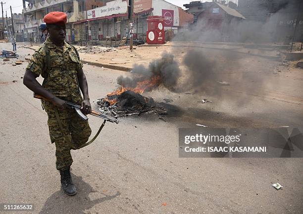 Ugandan military police officer walks past a burning barricade across a street in Kampala on February 19, 2016. Dozens of polling stations in Uganda...