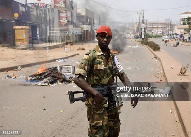 Ugandan military police officer walks past a burning barricade across a street in Kampala on February 19 during the second day of voting in...