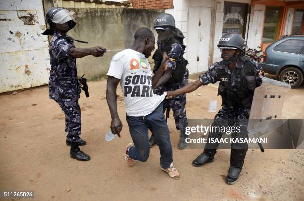 Ugandan police officer sprays tear gas onto a protestor after he was aprehended in Kampala on February 19 during the second day of voting in...