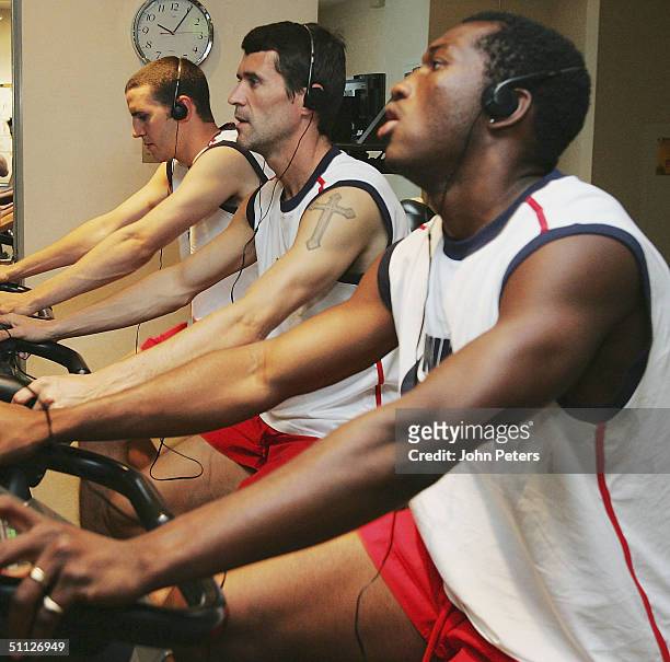 John O'Shea, Roy Keane and Eric Djemba-Djemba of Manchester United on exercise bikes during a gym session during their 2004 USA Tour, which is taking...