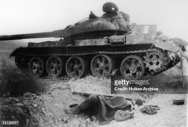 The body of a fallen Syrian soldier lies next to the ruins of a Soviet-built T-62 tank destroyed by the Israelis during the tank battle at Kuneitra...