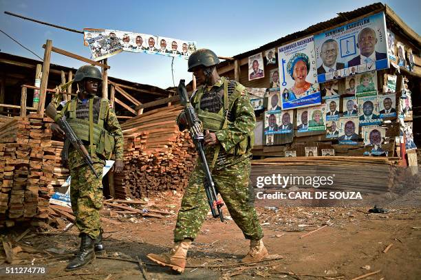 Ugandan soldiers walk past election posters in Kampala on February 19, 2016 during the presidential election vote. Voting was extended in 36 sites...