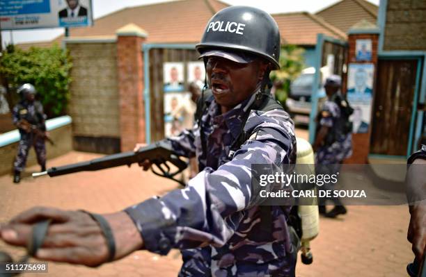 Ugandan police officer holding a tear-gas gun reacts after opposition leader Kizza Besigye was arrested at his party headquarters in Kampala, on...