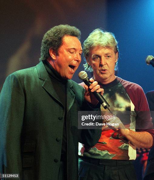 Musician Paul McCartney and singer Tom Jones on stage during