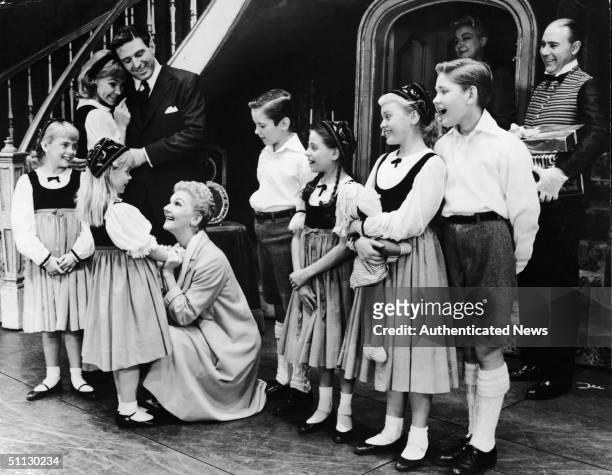 American actress Mary Martin kneels to hear some nrews from on of the von Trapp children in a scene from 'The Sound of Music' at the Lunt-Fontanne...