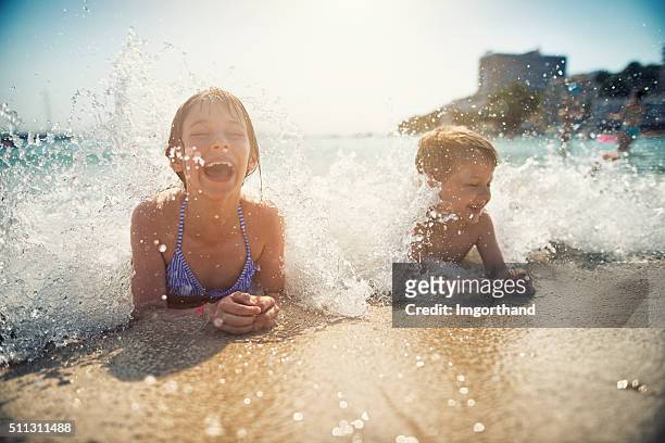 brother and sister having fun splashed in sea - droplet sea summer stockfoto's en -beelden