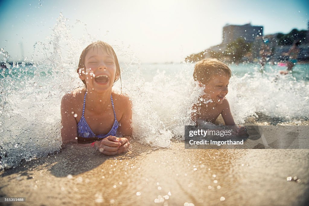 Brother and sister having fun splashed in sea