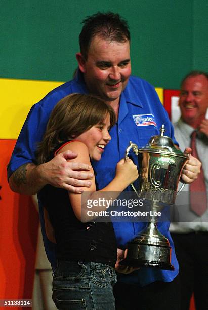 Phil Taylor hugs his daughter as they display the trophy after his victory over Mark Dudbridge in the Final of the Stan James World Matchplay Darts...