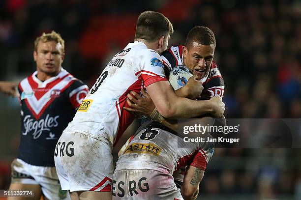 Kane Evans of Sydney Roosters is held up by James Roby, Travis Burns and Luke Thompson of St Helens during the World Club Series match between St...