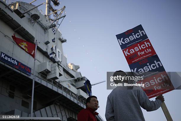 Volunteers hold campaign signs for John Kasich, governor of Ohio and 2016 Republican presidential candidate, before a campaign event at the Patriots...